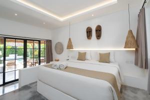 a white bedroom with a large bed with two pillows at Villa Ruta II - Luxury 2BR Tropical Villa next to Luna Beach Club and Nyanyi beach in Tanah Lot