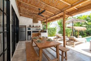 an outdoor kitchen and dining room with a wooden table at Villa Ruta II - Luxury 2BR Tropical Villa next to Luna Beach Club and Nyanyi beach in Tanah Lot
