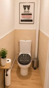 a bathroom with a toilet with a sign on it at Le cocon du lac in Montargis