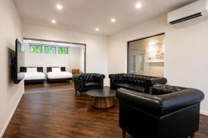 a living room with leather furniture and a bedroom at Comlien Villa Resort in Tateyama