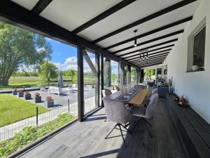 a dining room with a table and chairs and windows at Słoneczny Ogród - Ekskluzywna posiadłość nad wodą, Grill i Jacuzzi in Krzywińskie