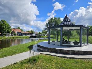 a gazebo in a park next to a river at Słoneczny Ogród - Ekskluzywna posiadłość nad wodą, Grill i Jacuzzi in Krzywińskie