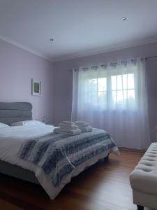 a white bedroom with a bed and a window at Camelias in Guimarães