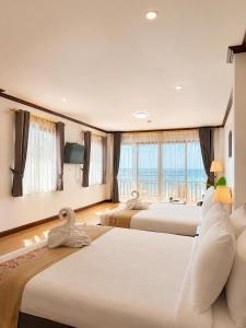 a hotel room with three beds and a large window at ClayHouse SAMUI Boutique Hotel in Koh Samui