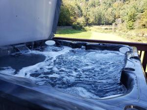 a hot tub filled with water next to a window at Riverbend Retreat in Todd
