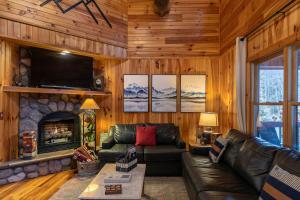 a living room with a leather couch and a fireplace at Riverbend Retreat in Todd +42 photos