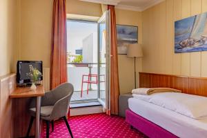 a hotel room with a bed and a desk and a window at Hotel Friese in Norderney