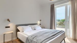 a white bedroom with a large bed and a window at Villa Moia by Villas Guide in Kaštelir