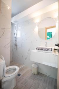a white bathroom with a toilet and a mirror at Ladina Comfort Studios in Lygia +30 photos