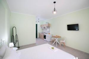 a white living room with a table and a tv at Ladina Comfort Studios in Lygia