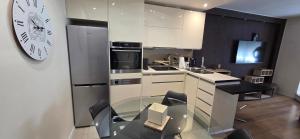 a kitchen with a glass table and a clock on the wall at Apartman Jo Ma MA in Solin