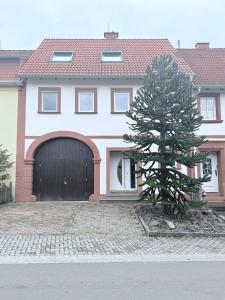 a tree in front of a house with a garage at Ferienhaus am Mühlenpfad in Ottweiler