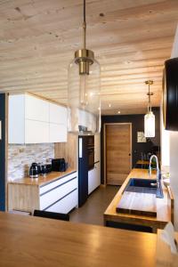 a kitchen with white cabinets and a wooden ceiling at Ouréa in Génos
