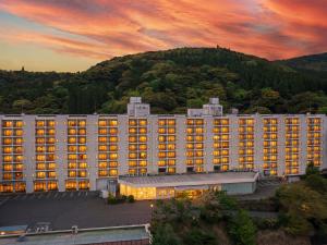 a large white building with a mountain in the background at Hotel Kirishima Castle in Kirishima