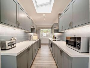 a large kitchen with gray cabinets and a skylight at High Dougarie Farmhouse in Dougarie