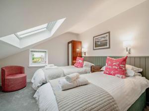 a bedroom with three beds and a red chair at High Dougarie Farmhouse in Dougarie