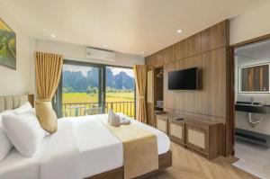 a bedroom with a large white bed and a television at Sunset Mountain View Resort in Vang Vieng