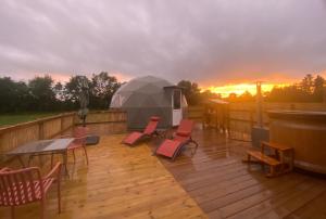 a deck with chairs and a table and an umbrella at le dôme avec bain nordique in Amfroipret