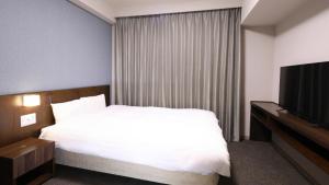 a hotel room with a bed and a television at Dormy Inn Wakkanai in Wakkanai