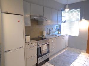 a kitchen with white cabinets and a sink and a refrigerator at Charming Villa close to the sea in Errindlev