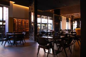 a dining room with tables and chairs and windows at Vila-L Hotel in Tirana