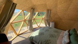 a bed in a room with a large window at le dôme avec bain nordique in Amfroipret