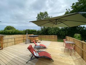 a deck with chairs and a table and an umbrella at le dôme avec bain nordique in Amfroipret +7 photos