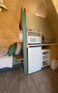 a room with a bed with a microwave and a refrigerator at le dôme avec bain nordique in Amfroipret
