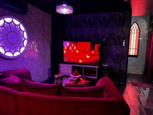 a living room with a couch and a tv at Les Secrets Rooms - Verdun in Verdun-sur-Meuse