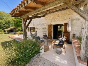 a patio with a table and chairs under a wooden roof at Authentique maison en pierre blanche du Quercy in Castelnau-de-Montratier