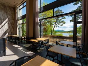 a room with tables and chairs and large windows at Tateshina Lake Resort in Tateshina