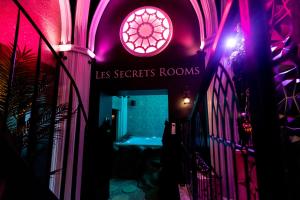 a hallway with a pink lighted room with a sign at Les Secrets Rooms - Verdun in Verdun-sur-Meuse