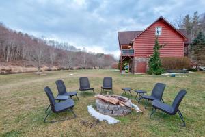 a group of chairs around a fire pit in front of a red barn at River Roost in Todd