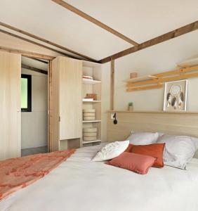a bedroom with a large white bed with red pillows at La forêt PALOMA, Ecolodge in Léon
