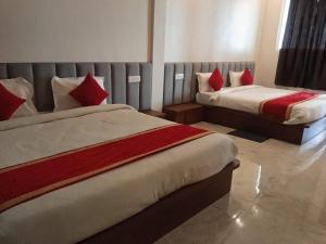 two beds in a hotel room with red pillows at The Kalindi Hotel and Resort in Hamīrpur
