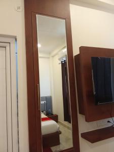 a mirror in a room with a bed and a television at The Kalindi Hotel and Resort in Hamīrpur