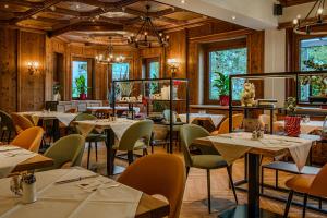 a dining room with tables and chairs and windows at Hotel Völserhof - Bergbahn im Sommer 2026 inklusive in Bad Hofgastein