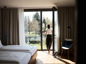 a woman walking into a hotel room looking out the window at Sternen Bohlingen Aparthotel in Bohlingen
