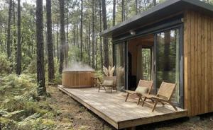 a cabin in the woods with chairs and a hot tub at La forêt PALOMA, Ecolodge in Léon