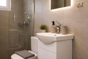 a bathroom with a sink and a toilet and a shower at Dorothy's Apartments Near Athens Airport By SEM in Artemida