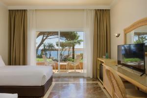 ein Hotelzimmer mit Bett, Fernseher und Balkon in der Unterkunft Eden Roc Hotel & Spa by Brava Hoteles in Sant Feliu de Guixols