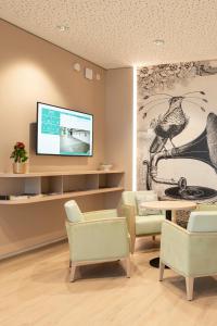 a living room with a tv and a table and chairs at Senevita Dreiklang in Lausen