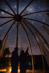 two people standing under an umbrella looking at the stars at Bubble Hotel in Coonabarabran