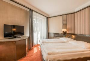 a hotel room with a bed and a flat screen tv at Hotel Monopol Luzern in Lucerne