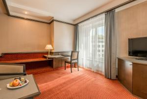 a hotel room with a table and a television at Hotel Monopol Luzern in Lucerne