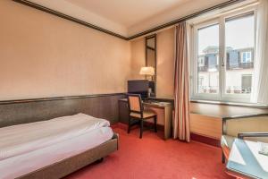 a hotel room with a bed and a desk and window at Hotel Monopol Luzern in Lucerne