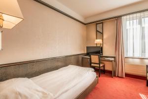 a hotel room with a bed and a desk at Hotel Monopol Luzern in Lucerne +34 photos