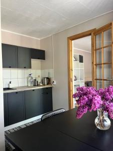 a kitchen with a table with a vase of purple flowers at Piejūras Namiņš in Ragaciems +18 photos