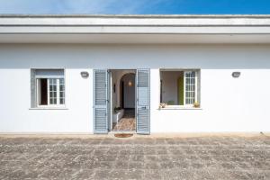 a white house with two windows and a door at Casa Libeccio in Gagliano del Capo