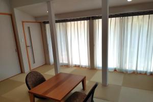 a table and chairs in a room with windows at 萩別邸 翠 HAGI Bettei SUI in Hagi